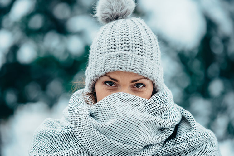 A woman with a fuzzy hat and scarf on in the snow