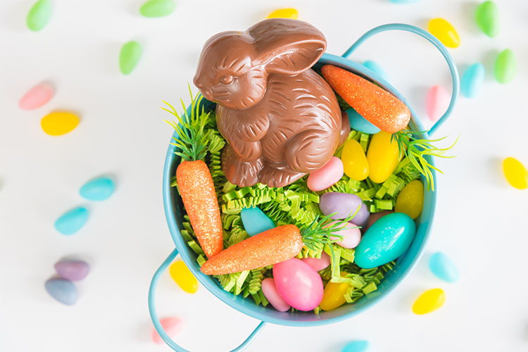An Easter basket full of candy, easter eggs, and a chocolate bunny.